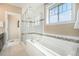 Bright bathroom features a soaking tub, glass shower enclosure, and a large window offering natural light at 8460 E 54Th Dr, Denver, CO 80238