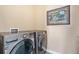A modern laundry room features side-by-side washer and dryer with an artistic decor piece at 8460 E 54Th Dr, Denver, CO 80238