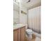 Bright bathroom with framed pictures, light wood cabinets, toilet and shower with patterned curtain at 1629 S Deframe St # B8, Lakewood, CO 80228