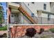Condo exterior showcasing a brick facade, black metal railing, wood stairs, and mature shrubs at 1629 S Deframe St # B8, Lakewood, CO 80228