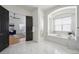Bright bathroom features a soaking tub with arch window, marble floor, and a bedroom view at 6425 Tremolite Dr, Castle Rock, CO 80108