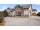 Beautiful home exterior with stone accents, three-car garage, and a circular driveway at 6425 Tremolite Dr, Castle Rock, CO 80108
