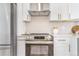 Close up of the new stainless steel oven with range hood and white cabinets in a renovated kitchen at 1240 S Chase Ct, Lakewood, CO 80232