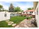 Backyard showcases a green lawn, storage shed, stone pathway, and access to the deck, ideal for outdoor enjoyment at 5885 S Huron St, Littleton, CO 80120
