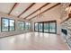 Spacious living room with beamed ceilings, hardwood floors, large windows, fireplace, and outdoor access at 5820 Powell Rd, Parker, CO 80134