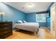 Bedroom featuring blue walls, hardwood floors, mounted TV, and bathroom access at 4994 S Independence Way, Littleton, CO 80123