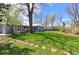 Large backyard featuring a well-manicured lawn, mature trees, and a charming blue house at 2561 S Carey Way, Denver, CO 80222