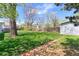 Spacious backyard with a lush lawn, mature trees, a storage shed, and a brick paver walkway at 2561 S Carey Way, Denver, CO 80222