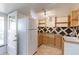 Compact kitchen features wooden cabinets, unique tile backsplash, and bright lighting at 2561 S Carey Way, Denver, CO 80222
