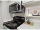 This kitchen has a black range oven, stainless steel microwave and a view into an adjacent room at 18391 E Kepner Pl # 205, Aurora, CO 80017