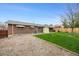 Wide shot of a brick home's backyard featuring grass and gravel, a green awning, and wood fencing at 1185 Yank St, Golden, CO 80401