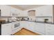 Well-lit kitchen featuring white cabinetry, updated appliances, and hardwood flooring at 1185 Yank St, Golden, CO 80401
