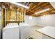 Unfinished laundry room with exposed wood beam ceiling, utility sink, and a newer washer and dryer at 1185 Yank St, Golden, CO 80401