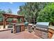 Outdoor kitchen featuring stone counters, stainless appliances and covered wooden structure at 4649 Spinning Wheel Dr, Brighton, CO 80601