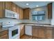 A sunlit kitchen featuring wood cabinets, modern appliances, and a view of the outdoors from the window at 19249 E 58Th Ave # D, Denver, CO 80249