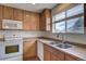 A well-lit kitchen featuring wood cabinets and modern appliances and a double sink beneath a window at 19249 E 58Th Ave # D, Denver, CO 80249