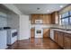 Spacious kitchen featuring a laundry closet, wood cabinets, modern appliances, and wood floors at 19249 E 58Th Ave # D, Denver, CO 80249