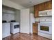 Spacious kitchen featuring a laundry closet, wood cabinets, modern appliances, and wood floors at 19249 E 58Th Ave # D, Denver, CO 80249