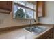 Close-up of kitchen sink, faucet, and countertop with wood cabinets and a window in the background at 19249 E 58Th Ave # D, Denver, CO 80249
