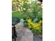 Backyard patio with an outdoor table and chairs surrounded by lush landscaping with yellow flowers at 5461 S Youngfield Ct, Littleton, CO 80127