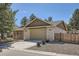 Front exterior featuring a two-car garage, brick facade, mature trees, and tasteful landscaping at 5461 S Youngfield Ct, Littleton, CO 80127