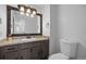 Bathroom with granite countertops, wood cabinetry, a vanity sink, and an elongated toilet at 1716 W Sunset St, Longmont, CO 80501