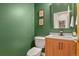 Stylish powder room with green walls, modern fixtures, framed art and a decorative mirror at 670 Independence Dr, Larkspur, CO 80118