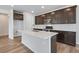 A kitchen island has bar seating, stainless steel appliances, and dark cabinets with bright countertops at 6881 Oak Canyon Cir, Castle Pines, CO 80108