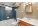 Bathroom with blue tiles in the shower/bath and wood framed mirror and vanity at 8235 Auburn Ln, Westminster, CO 80031