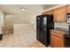 Open kitchen area with tile flooring and black refrigerator at 8235 Auburn Ln, Westminster, CO 80031
