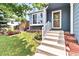 Inviting front entrance with a well-kept lawn, colorful flowers, and a charming front porch at 8977 W Toller Ave, Littleton, CO 80128