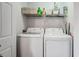 Functional laundry room with white appliances and convenient overhead storage shelving at 12063 Monaco Ct, Brighton, CO 80602