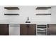 Modern wet bar includes a stainless steel dishwasher, wine fridge, quartz counters, and stylish floating shelves at 4236 Zuni St, Denver, CO 80211