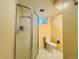 Bathroom with tile floors, shower stall, and a toilet with yellow walls at 2964 S Yates St, Denver, CO 80236