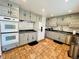 Spacious kitchen with gray cabinets, black countertops, and modern appliances on brick floor at 2964 S Yates St, Denver, CO 80236