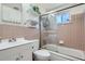 Updated bathroom featuring pink tiling, glass shower door, and vanity with storage at 1781 Uinta St, Denver, CO 80220