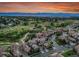 An aerial view capturing the neighborhood's layout, set against a backdrop of mountains and an orange sky at sunset at 9246 Sori Ln, Highlands Ranch, CO 80126