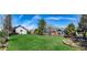 Expansive backyard with a large green lawn, bordered by a brick-lined flowerbed and a wooden fence at 2912 Lake Park Way, Longmont, CO 80503
