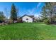 Well-maintained backyard with lush grass and mature trees, showcasing the home's exterior and landscaping at 2912 Lake Park Way, Longmont, CO 80503