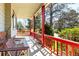 Cozy front porch with red railings and supports, benches, and a view of the lush, landscaped yard at 2912 Lake Park Way, Longmont, CO 80503