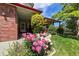 Inviting entryway featuring beautiful pink and white peonies, red brick accents, and a covered porch at 2912 Lake Park Way, Longmont, CO 80503