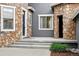 Inviting front porch area featuring stone accents, a modern black door, and gray concrete steps at 2832 Danbury Ave, Highlands Ranch, CO 80126