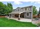 Rear exterior of the home highlighting the large backyard, lush lawn, and covered patio with stone columns at 2832 Danbury Ave, Highlands Ranch, CO 80126