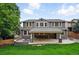Back of the house showcasing the covered patio, stone fire pit, large backyard, and manicured lawn at 2832 Danbury Ave, Highlands Ranch, CO 80126