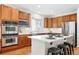 Modern kitchen with stainless steel appliances, wooden cabinetry, island with barstools, and white subway tile backsplash at 2832 Danbury Ave, Highlands Ranch, CO 80126
