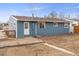 Home back exterior featuring blue siding, a small brick patio, and a practical entrance at 4211 E 69Th Ave, Commerce City, CO 80022