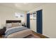 Staged bedroom featuring a comfortable bed, window with blue curtains, and natural light at 4211 E 69Th Ave, Commerce City, CO 80022