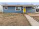 Charming single-story home featuring a blue exterior, a bright yellow front door, and a covered front porch at 4211 E 69Th Ave, Commerce City, CO 80022