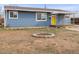 Cozy blue single-story home with a small brick-lined firepit in the front yard at 4211 E 69Th Ave, Commerce City, CO 80022