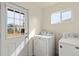 Laundry room with white front-loading washer and dryer and a view to the back yard at 4211 E 69Th Ave, Commerce City, CO 80022
